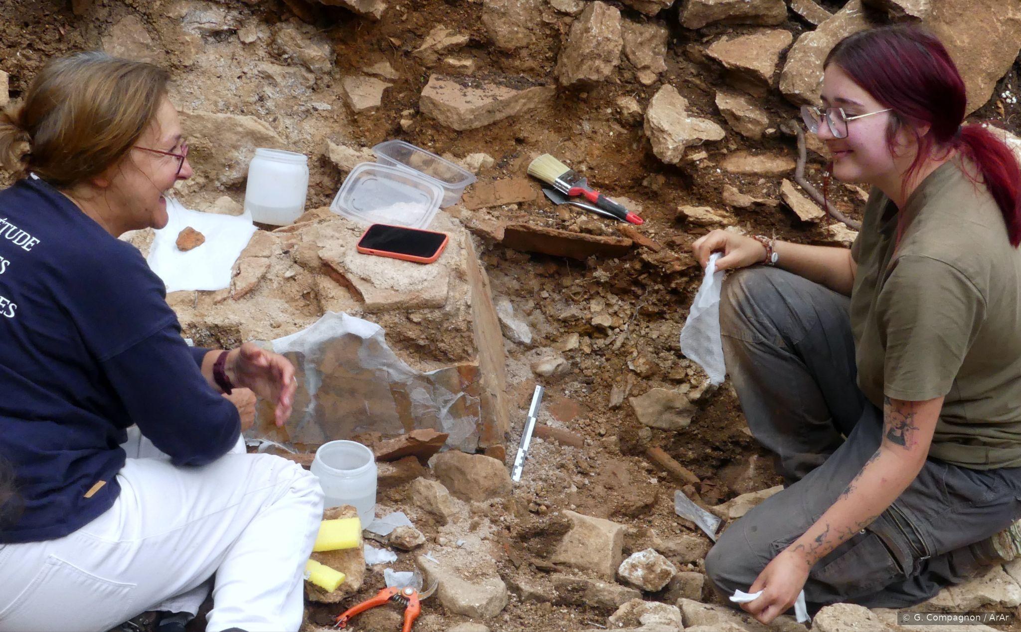 Deux archéologues, professionnelle et étudiante, en train de conditionner des objets sur le chantier.